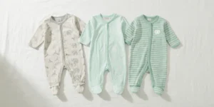 A wide banner-style flat lay of three Simple Joys by Carter's unisex baby sleep and play outfits arranged horizontally on a white background, featuring light grey elephant print, white giraffe print on mint green, and soft mint green stripes.