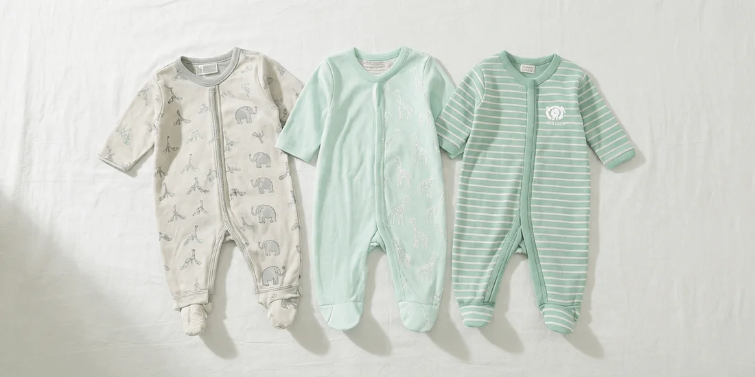 A wide banner-style flat lay of three Simple Joys by Carter's unisex baby sleep and play outfits arranged horizontally on a white background, featuring light grey elephant print, white giraffe print on mint green, and soft mint green stripes.