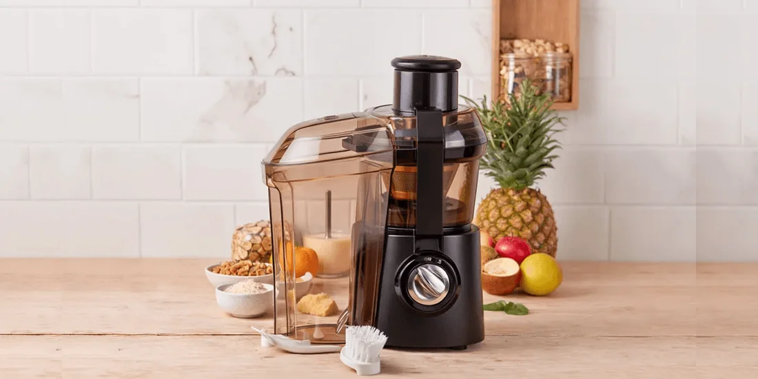 Hamilton Beach Big Mouth juicer with a whole apple entering the extra-large 3-inch feed chute, showcasing its no-prep juicing capability.